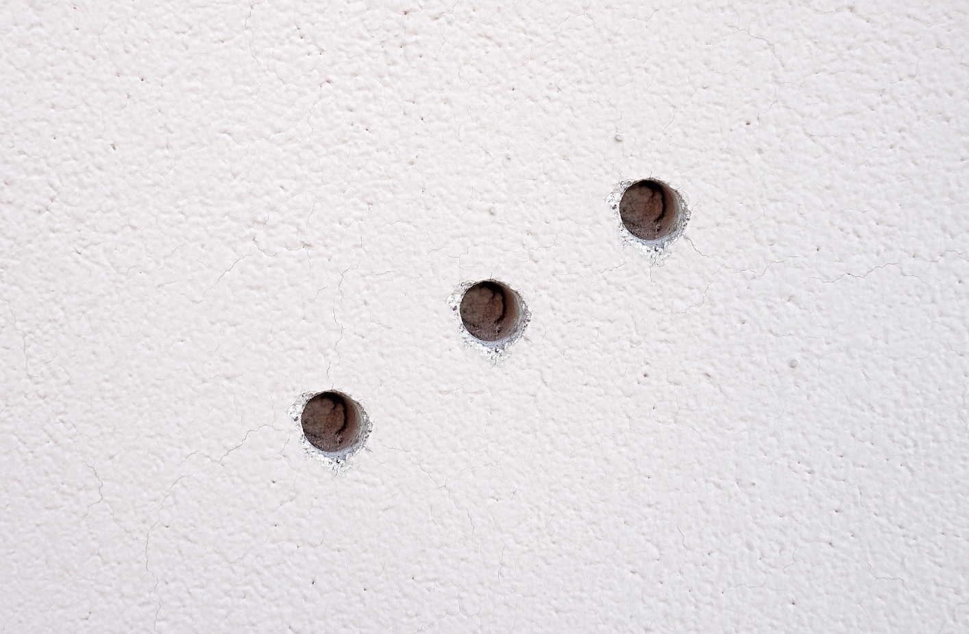 Trzy małe dziury w ścianie po wyjęciu kołk&oacute;w lub gwoździ &ndash; powierzchnia do wypełnienia