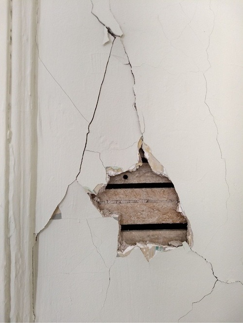 Pęknięcia i ubytki w tynku na ścianie &ndash; przykład powierzchni wymagającej naprawy masą szpachlową